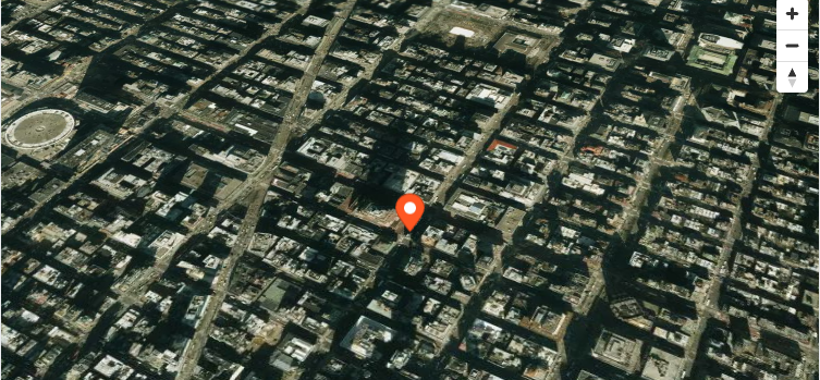 Satellite aerial imagery of a city center shown as a MapLibre GL JS basemap.